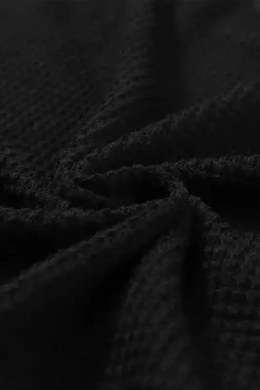 Close-up of black waffle knit fabric texture from Chic Knit Top - Plus Size Moss Green | Long Sleeve Style, showing soft and cozy weave.
