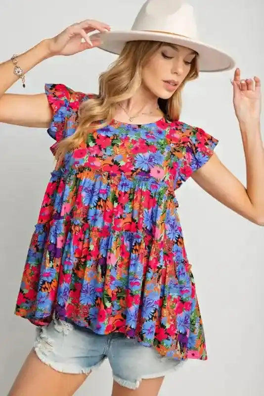 Floral babydoll top for women styled with a hat and shorts, featuring a flowy fit and colorful floral print for daily wear.