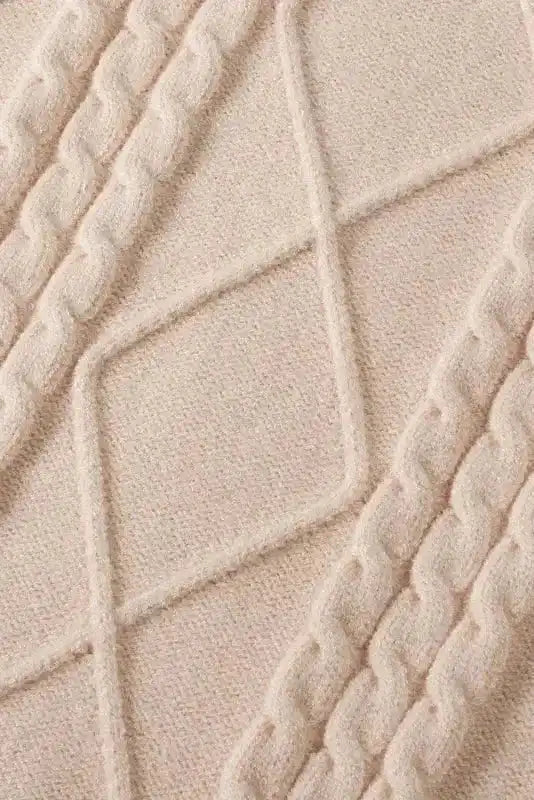 Close-up of oatmeal plus cable knit sweater fabric showing detailed diamond and cable knit texture in soft, cozy yarn.