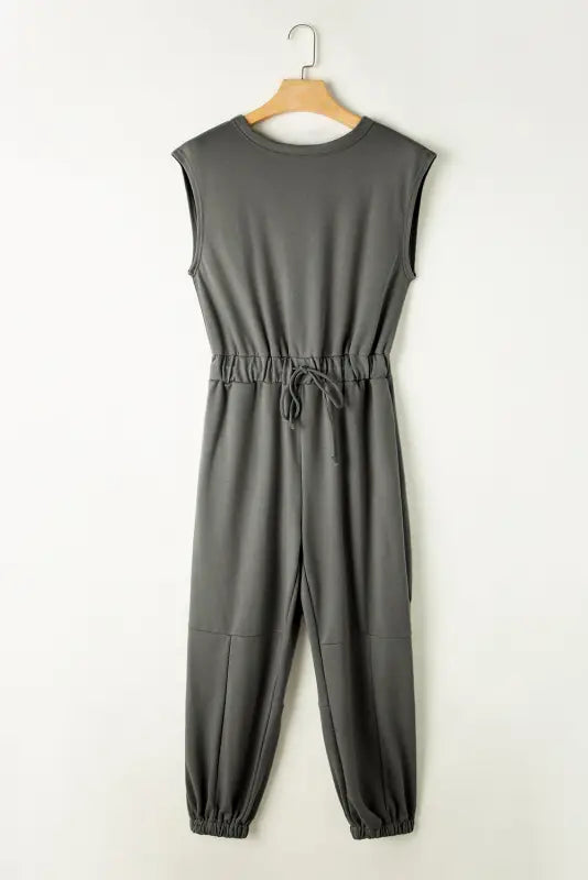 Gray open back drawstring jogger jumpsuit with elastic waistband on wooden hanger