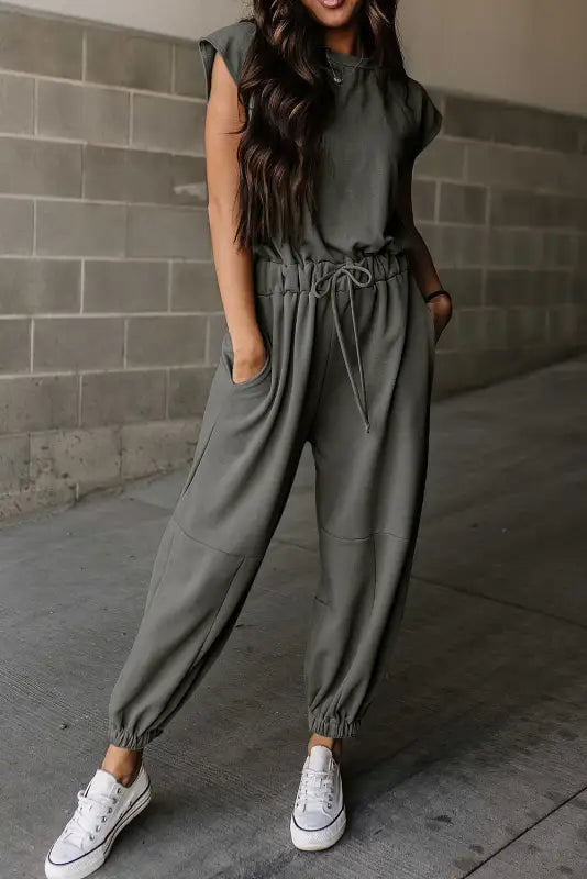 Gray jogger jumpsuit with drawstring waist and white sneakers for a relaxed look