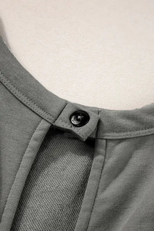 Close-up of gray fabric with button closure on open back drawstring jogger jumpsuit