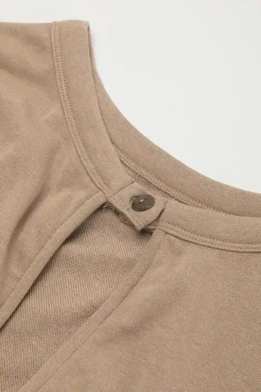 Close-up of back button closure on beige open back jogger jumpsuit, highlighting keyhole detail and soft fabric.