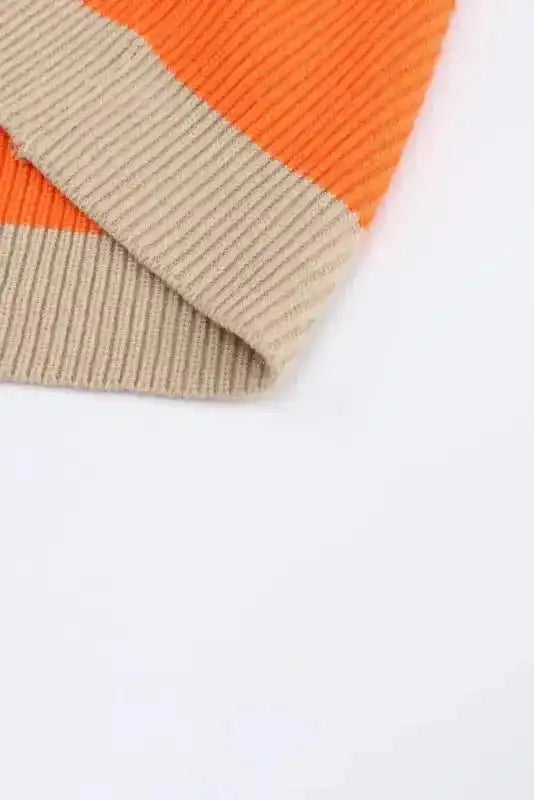 Detailed view of hem on orange colorblock cardigan, showing ribbed knit texture and clean stitching for a polished finish.
