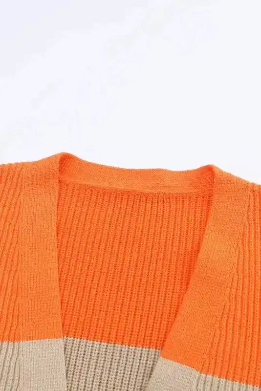Neckline detail of orange cardigan with ribbed knit and colorblock design, highlighting the open-front collar and vibrant color.