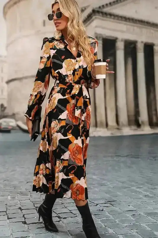 Model walking in Orange Floral Tie Neck Dress with coffee cup, showcasing elegant flow and flattering fit for everyday wear.