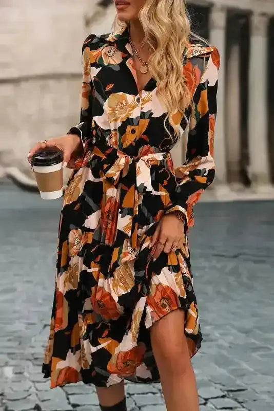 Model wearing Orange Floral Tie Neck Dress with long sleeves and pleated skirt, styled for a chic daily or vacation look.