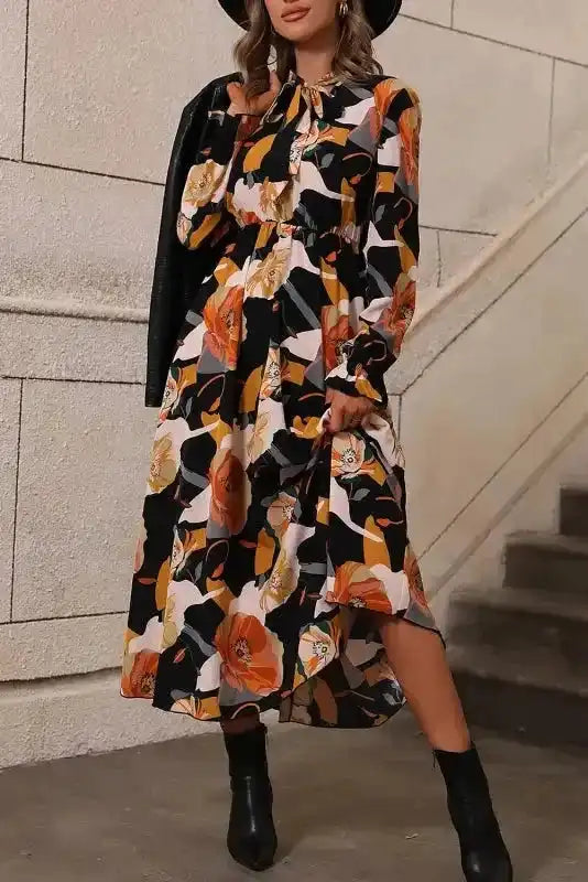 Orange floral long sleeve dress styled with black ankle boots and jacket, featuring a tie neck and flattering high waist.