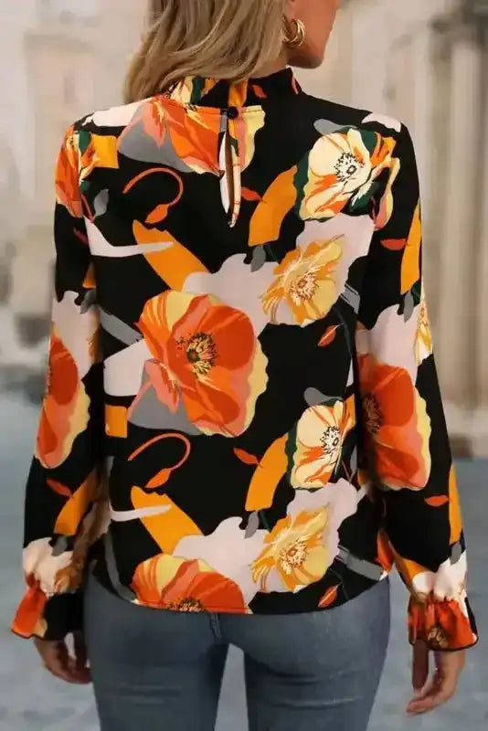 Back view of floral print blouse with keyhole closure and ruffled cuffs, perfect for everyday wear.