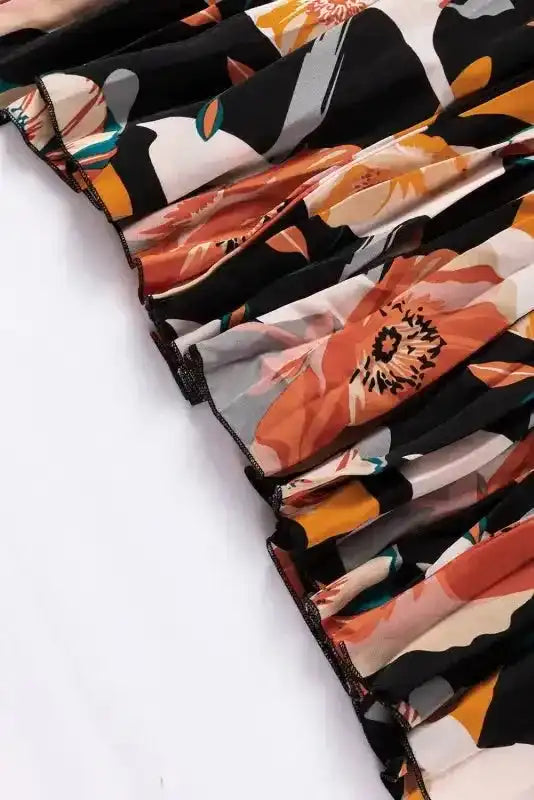 Hemline of Orange Floral Tie Neck Dress with pleated A-line silhouette and multicolor floral print on soft fabric.