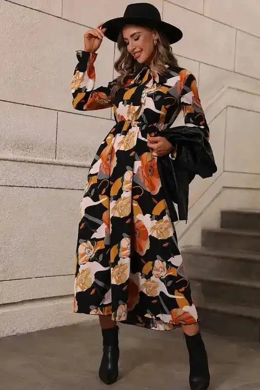 Southern Belle style orange floral tie neck dress with long sleeves, styled with a black hat and boots for a chic look.