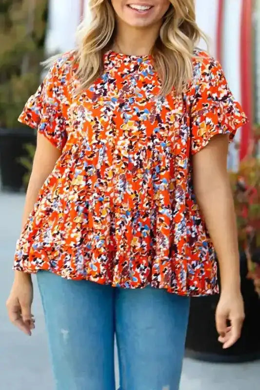 Orange floral peplum blouse with ruffle sleeves in curvy fit, styled with blue jeans for a casual yet feminine look.