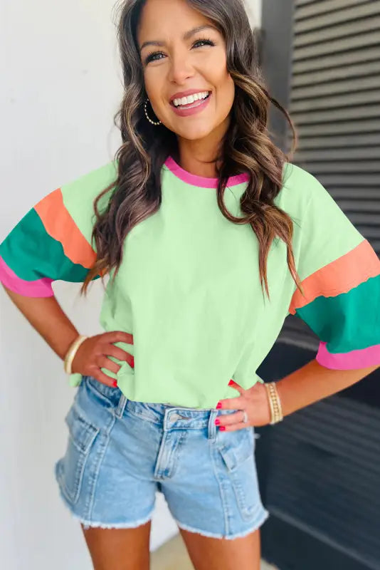 Woman in colorful striped oversized stitched top, denim shorts, smiling brightly. Relax relax relax