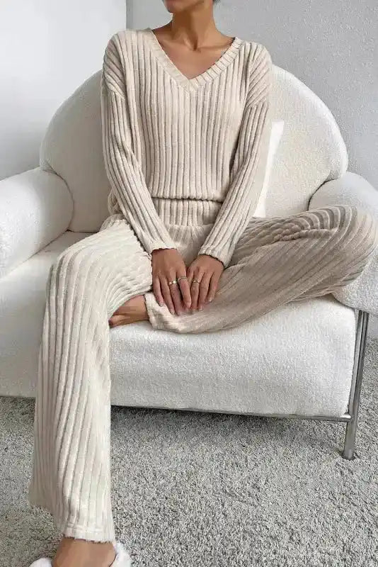 Seated view of beige ribbed V-neck pullover pants set in plus size, showcasing soft stretch fabric and wide-leg silhouette.
