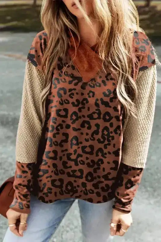 Leopard print Patchwork Hoodie with oversized fit and textured knit sleeves, styled with jeans for a trendy streetwear look.