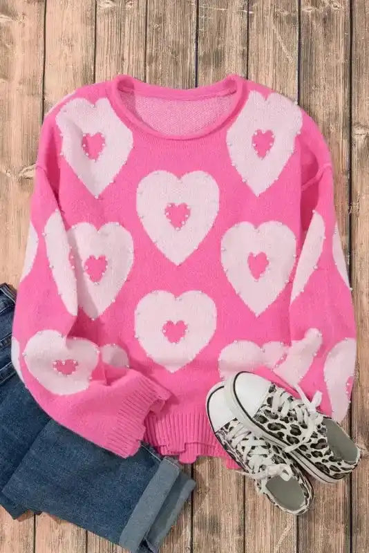 Flat lay of pink heart sweater with jeans and leopard sneakers, ideal for casual Valentine's Day outfits.