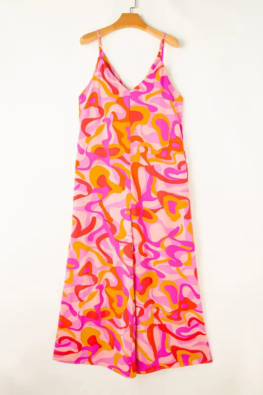 Pink boho jumpsuit: wide leg abstract print in pink, orange, and red on wooden hanger