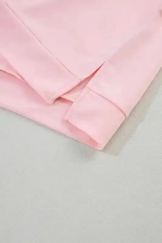 Close-up of hem detail on the Ladies Pink Polo V-Neck Top, showing side slit and fine stitching for a polished summer look.