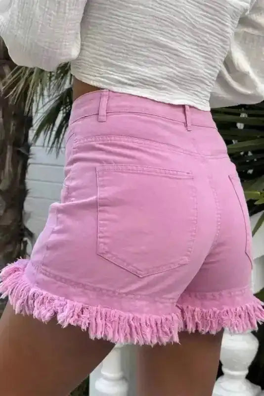 Back view of pink mid rise denim shorts featuring frayed hem and stretch cotton, ideal for casual summer outfits.