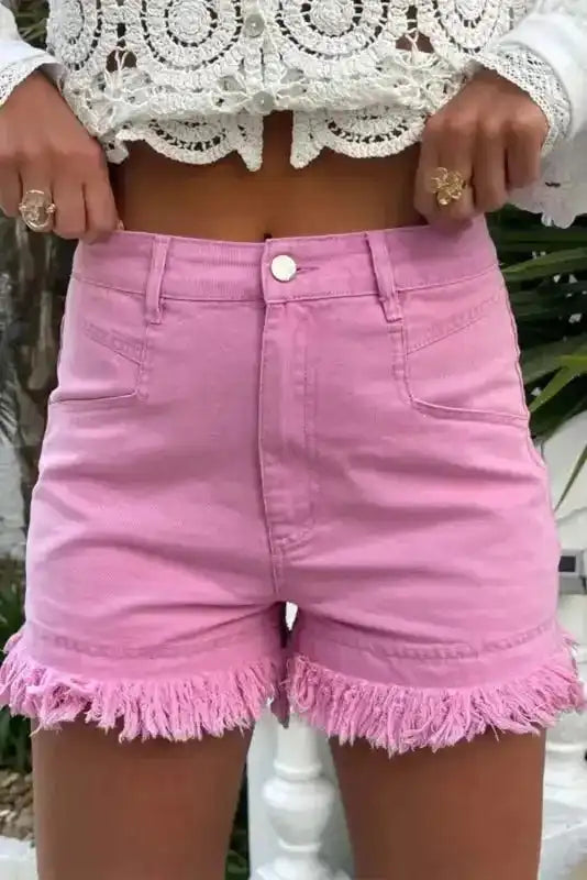 Ladies pink mid rise denim shorts with frayed hem and stretch cotton, styled with a white lace crop top for summer wear.