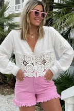 Woman wearing pink mid rise denim shorts with frayed hem and stretch cotton, styled for summer festival fashion.