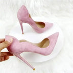 Hand holding Luxury Pumps - Pink Velvet High Heels Stiletto Shoes showcasing slim heel and scalloped edge. Ideal for upscale fashion ensembles.