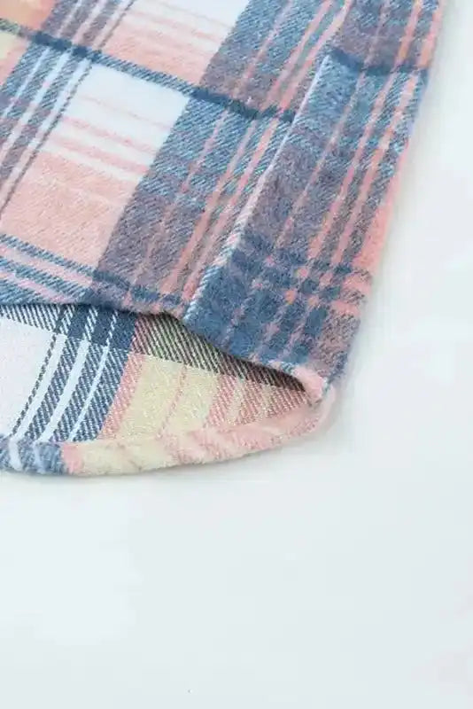 Hem detail of plaid shacket flap pockets in pastel tones, highlighting curved edge and cozy fall outerwear design.