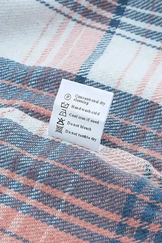 Care label on plaid shacket with flap pockets, indicating hand wash and cool iron instructions for fall outerwear maintenance.