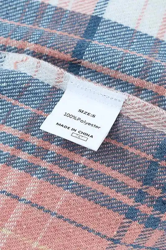Size and material label of stylish plaid shacket, showing 100% polyester fabric and made in China tag for fall fashion outerwear.