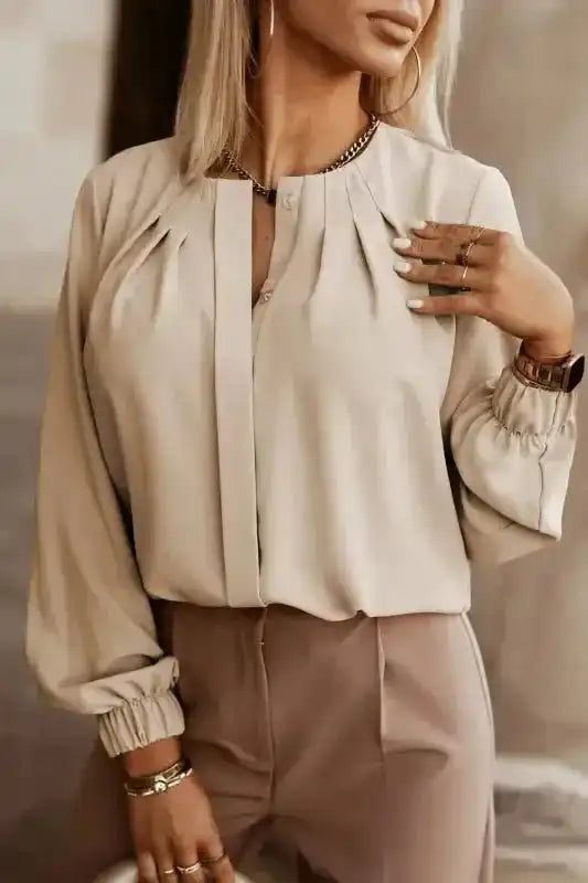 Beige Pleated Neck Stretch Cuff Shirt styled with taupe trousers. A versatile women's blouse for work or weekend looks.
