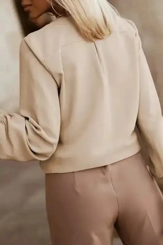 Back view of beige Pleated Neck Stretch Cuff Shirt on model, displaying relaxed fit and gathered cuffs for elegant women's fall tops.