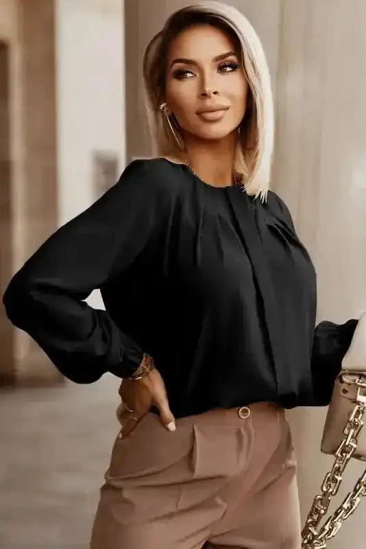 Model wearing black Pleated Neck Stretch Cuff Shirt paired with high-waisted beige pants. A chic women's top for daily elegance.