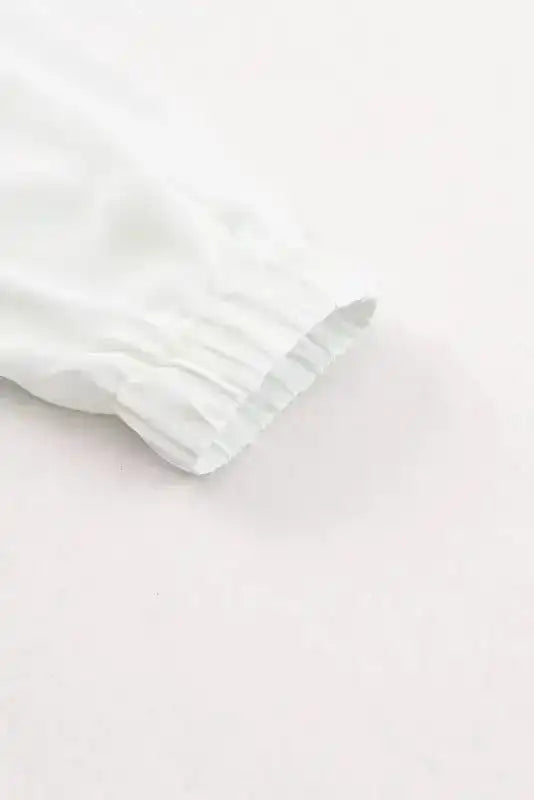 Detail of stretch cuff on white Pleated Neck Stretch Cuff Shirt, offering comfort and style in women's elegant fall tops.