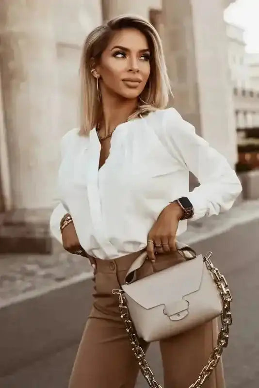 Model wearing white Pleated Neck Stretch Cuff Shirt with beige pants and chain handbag. A classy blouse for daily wear.