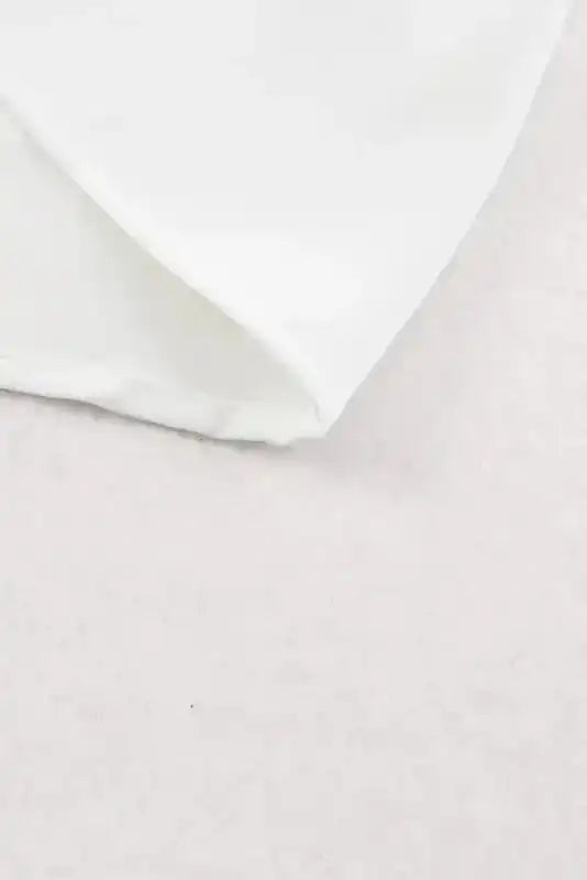 Hem detail of the Pleated Neck Stretch Cuff Shirt in white, showing clean stitching and smooth fabric for a tailored look.