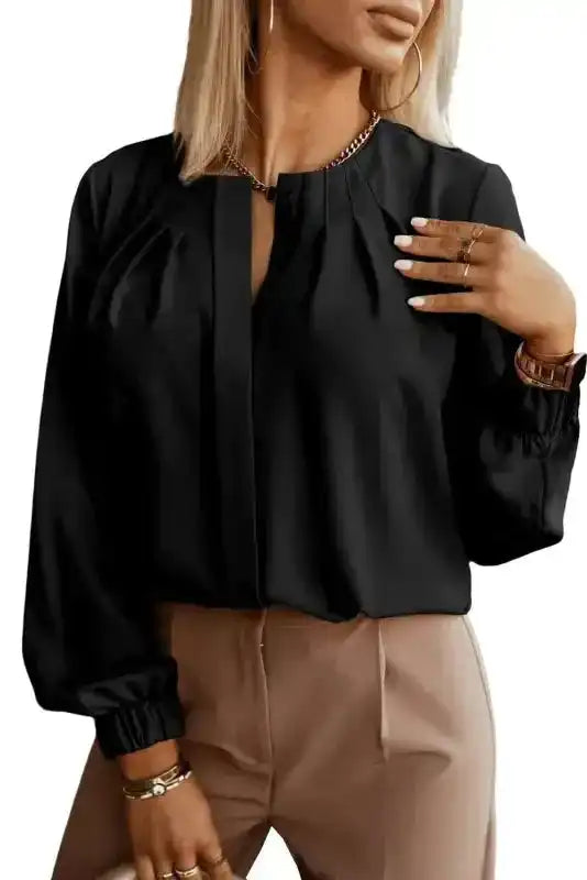 Close-up of black Pleated Neck Stretch Cuff Shirt highlighting pleated neckline and stretch cuffs. A best-selling elegant top.
