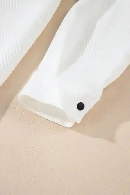 Cuff detail of white textured plus size jacket with black snap button, designed for comfort and winter practicality.