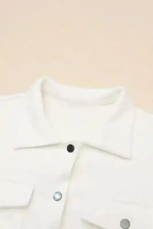 Close-up of collar and upper chest area of a white textured plus size jacket, highlighting the soft fabric and button detail.