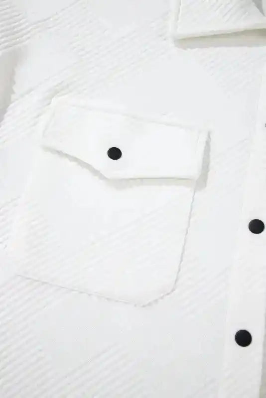 Detail of front chest pocket with black button on a white textured plus size jacket, showcasing its stylish pattern and structure.