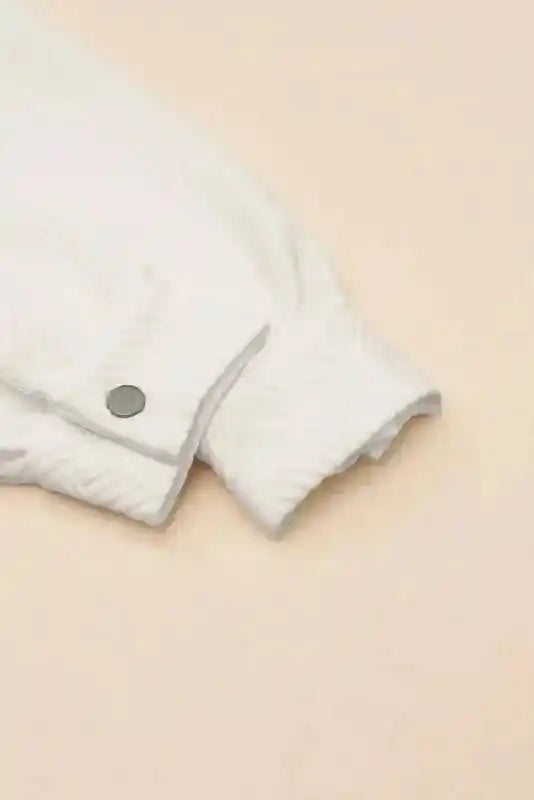 Close-up of cuff and snap button detail on textured plus size jacket, showcasing ribbed fabric and winter-ready design.