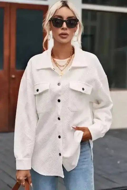 White plus size jacket with textured fabric and black buttons, styled with sunglasses and layered necklaces for a chic winter look.