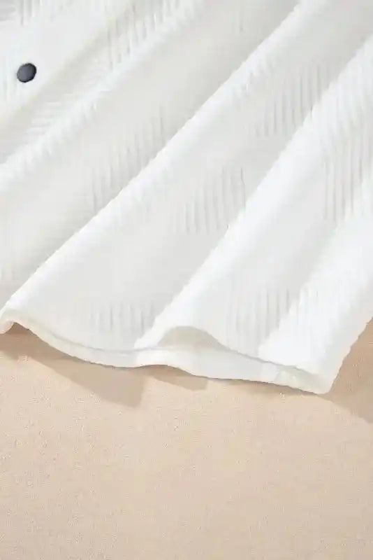 Hem detail of white textured plus size jacket, showing curved edge and ribbed fabric for a polished winter look.