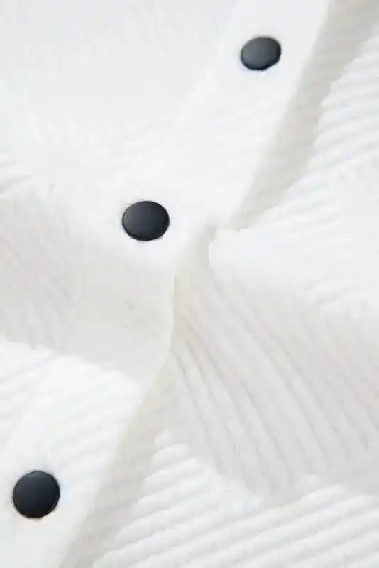 Close-up of white textured fabric with black snap buttons on a plus size jacket, highlighting the ribbed winter material.