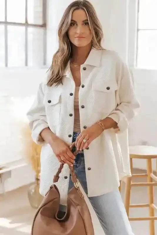 Casual winter outfit featuring a white plus size textured jacket with front pockets and black buttons, styled with a brown handbag.