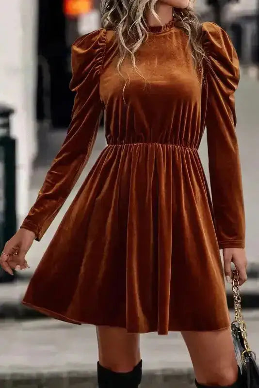 Chestnut velvet swing dress with frilled neck and gigot sleeves, styled with black boots for a chic winter look.