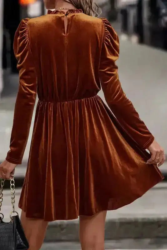 Back view of chestnut velvet swing dress featuring puffed gigot sleeves and gathered waist, ideal for festive occasions.