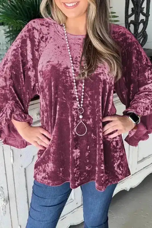 Velvet Pagoda Sleeve Top in Red Dahlia with crew neck and ruffled sleeves, styled with jeans for a chic winter look.