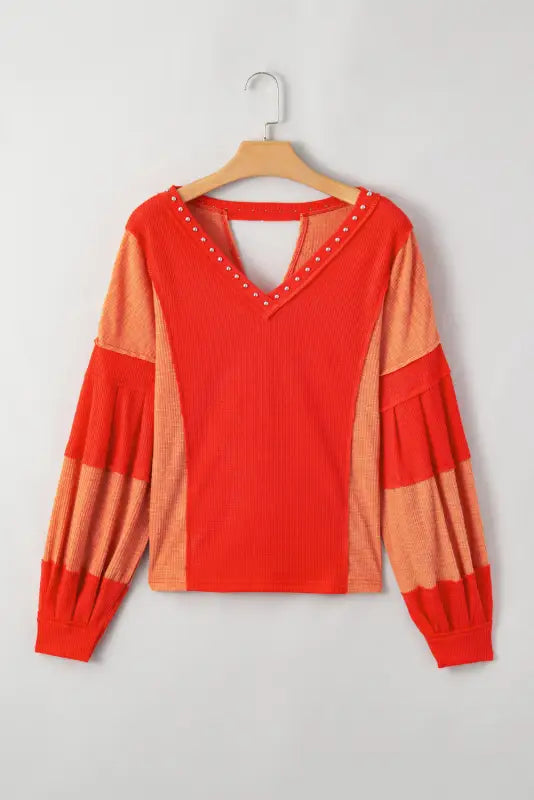 Red studded v neckline exposed seam textured knit top