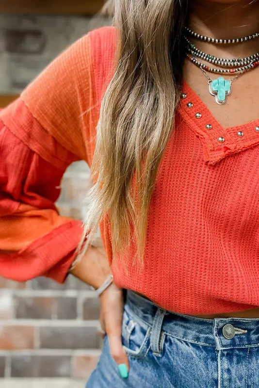 Red studded v neckline exposed seam textured knit top