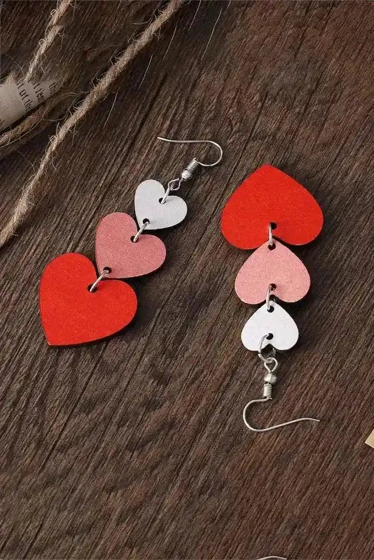 Tiered Heart Valentine's Earrings in red, pink, and white shown flat on wood, highlighting the playful cascading heart design.